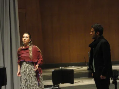 Ferzan in a red shawl performing a scene with a male singer on stage